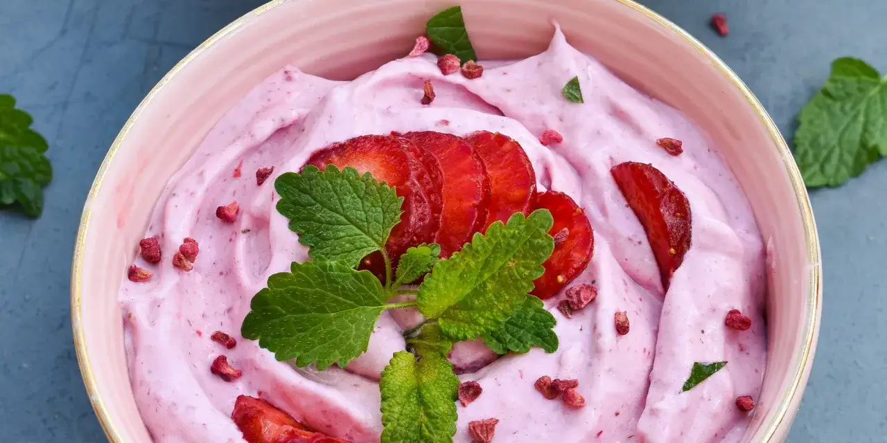 Keso glass med jordgubbar och mynta. En rosa, kr&auml;mig dessert med skivade jordgubbar och torkade hallon.