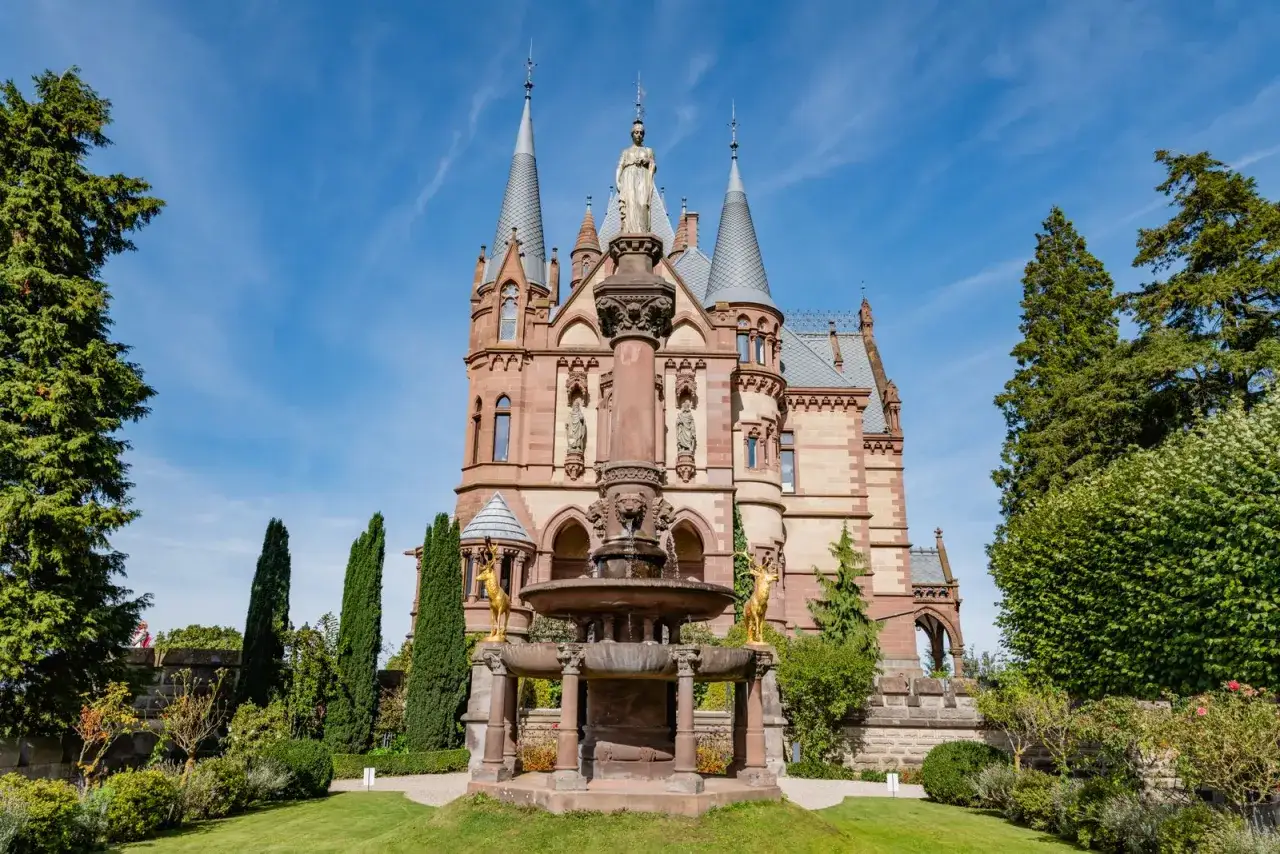 Ein M&auml;rchenschloss mit T&uuml;rmchen und einem Brunnen, das pure Romantik Architektur ausstrahlt.