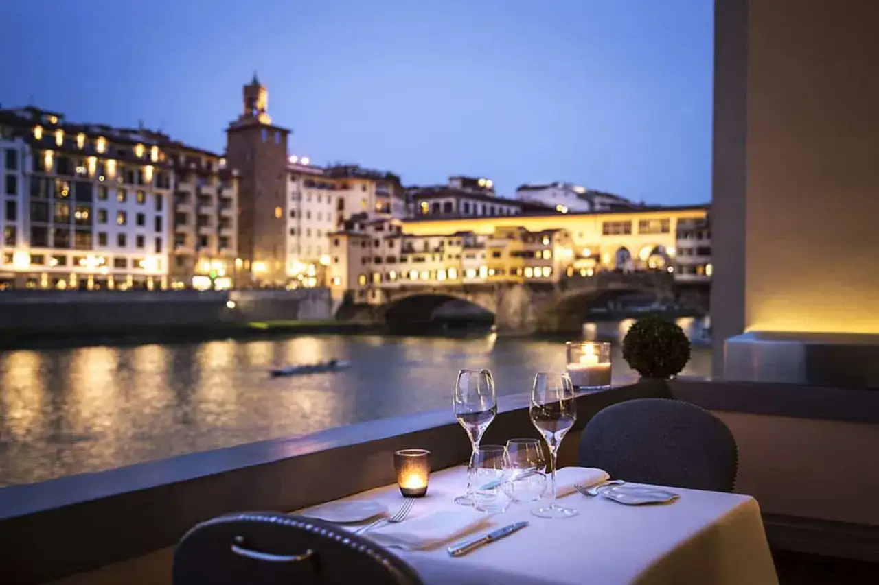 Tavola apparecchiata con vista su Ponte Vecchio, Firenze. Un'ambientazione perfetta per scoprire i migliori ristoranti di Firenze.