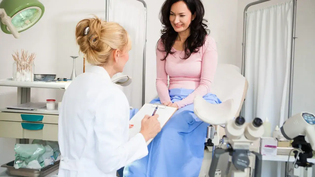 Lekarka rozmawia z pacjentką przed zabiegiem biopsji endometrium. Gabinet ginekologiczny z aparaturą medyczną.