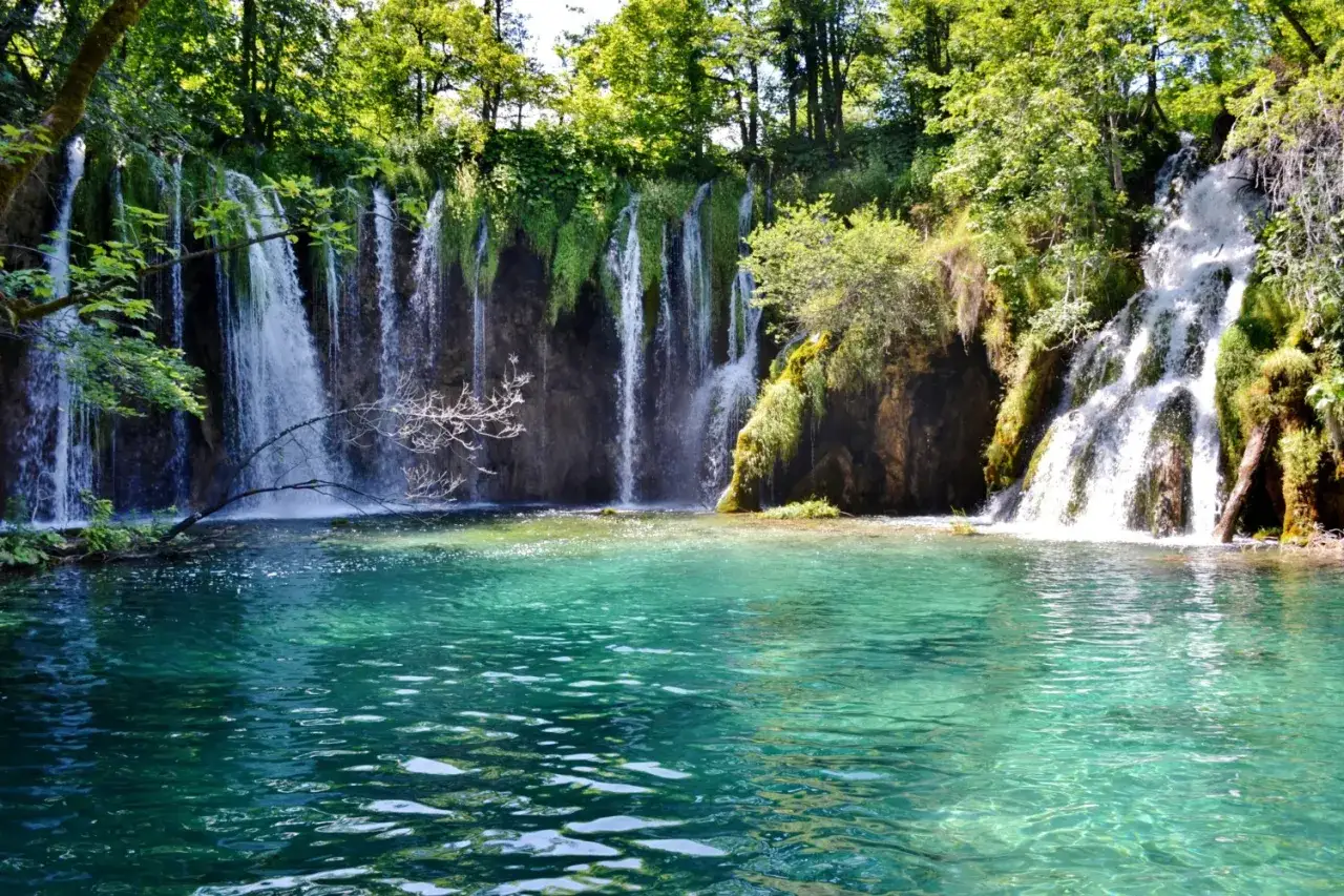 Cascate e acque cristalline nei Laghi di Plitvice, un paradiso naturale con vegetazione lussureggiante.