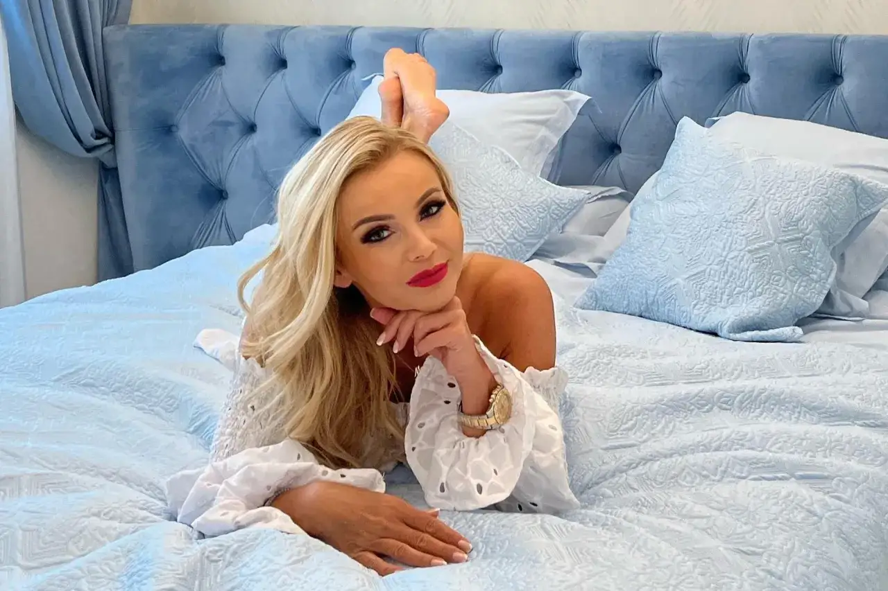 Monika Chwajoł, wiek nieznany, leży na łóżku w białej bluzce z bufiastymi rękawami.