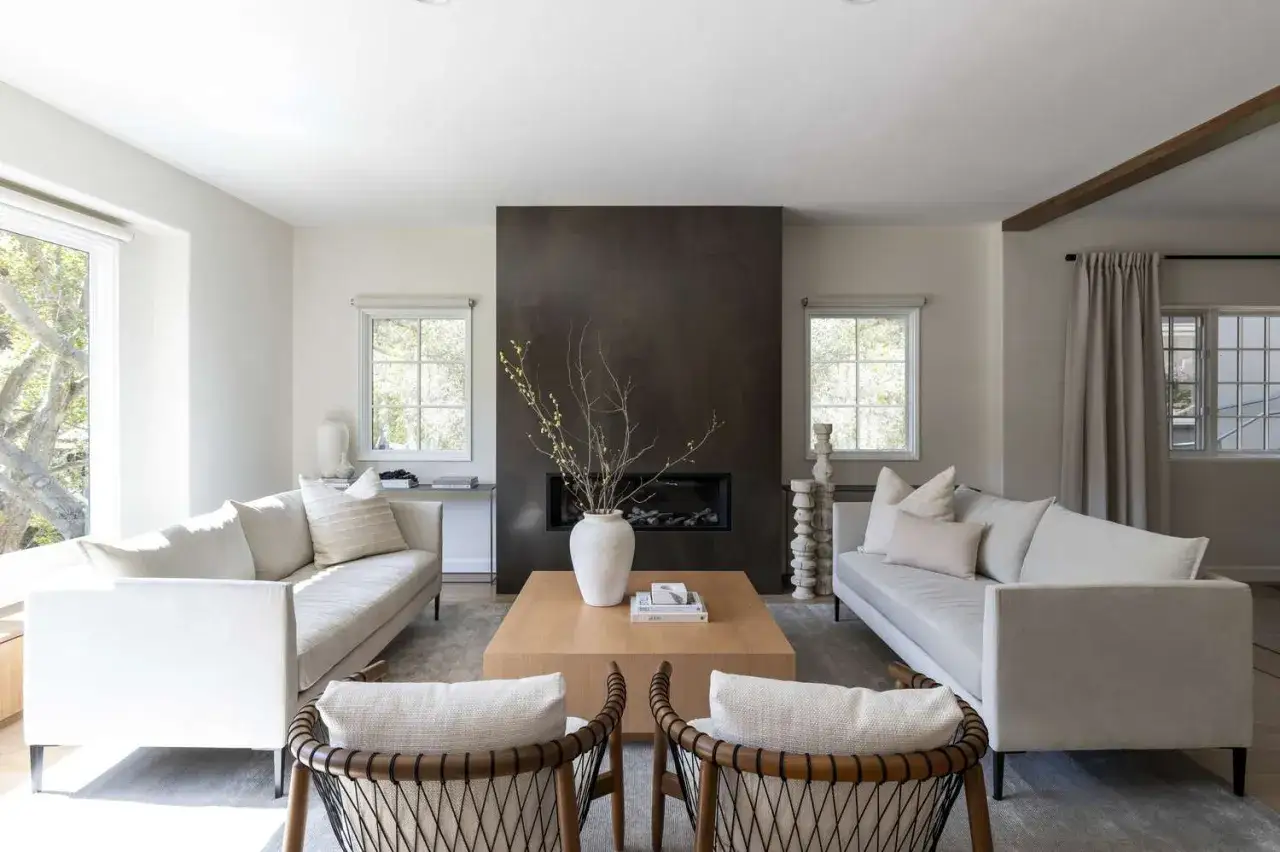 Modernes Wohnzimmer mit zwei Sofas, einem Holztisch und einem dunklen Kamin. Ausmisten befreit – hier herrscht klare Linienführung und Ruhe.
