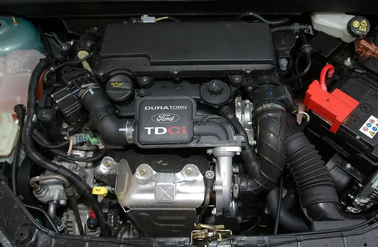 Silnik Duratorq TDCi z Ford Fiesta 2005. Widoczny akumulator i elementy układu dolotowego.