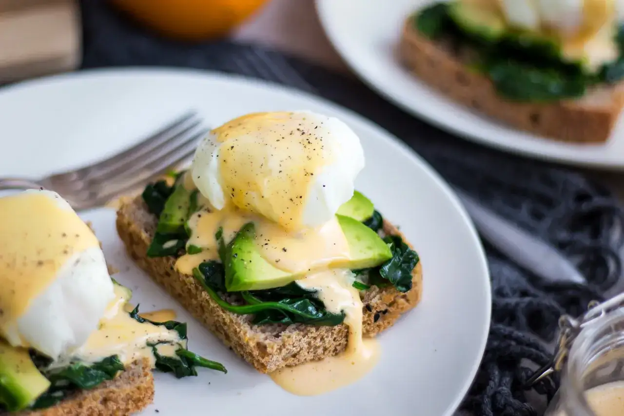 Pyszne jajka po florencku na tostach z awokado i szpinakiem, polane aksamitnym sosem holenderskim. Idealne na brunch!