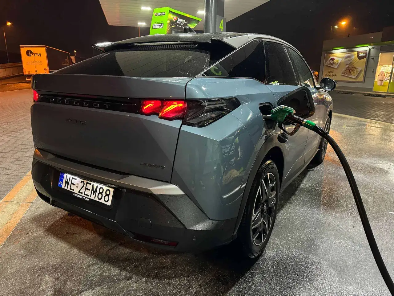 Szary Peugeot 3008 Hybrid tankuje paliwo. Kierowca dba o niskie peugeot 3008 spalanie.
