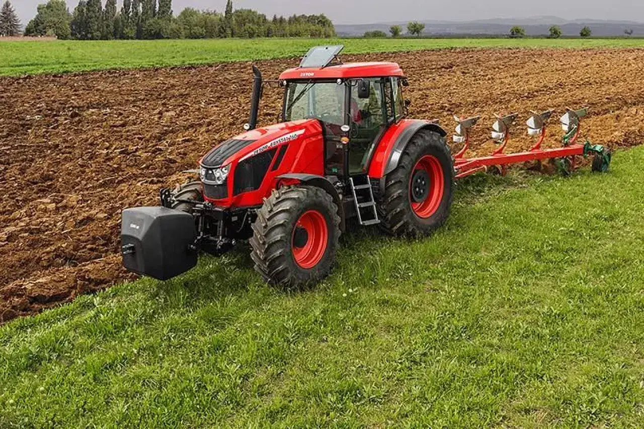 Czerwony Zetor Crystal z pługiem orze pole, przygotowując ziemię do siewu.