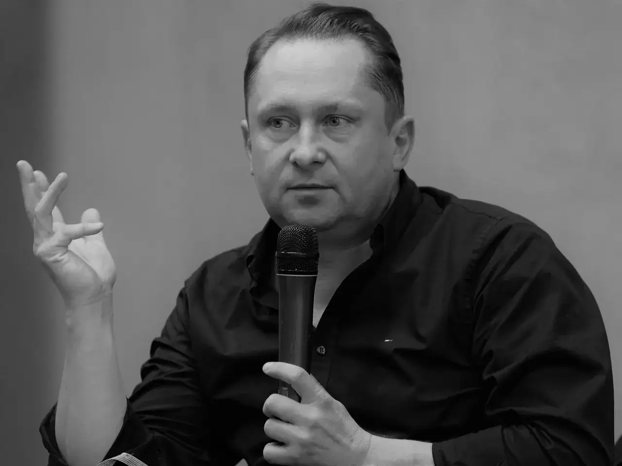 Kamil Durczok, znany z Faktów TVN, przemawia do mikrofonu, gestykulując.