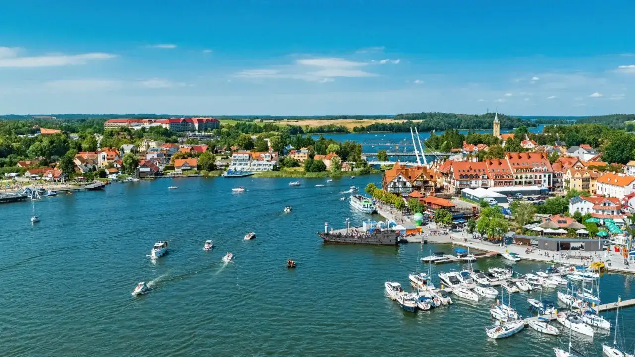 Malownicze Mikołajki i okolice tętnią życiem. Widok na port pełen łodzi, urokliwe kamieniczki i błękitne jezioro zachęcają do odkrywania atrakcji.