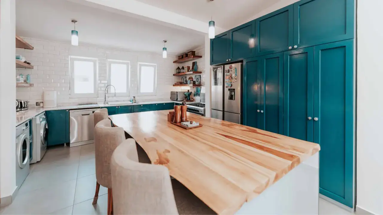 A modern kitchen featuring striking teal cabinets, a popular kitchen cabinet color, complemented by a warm wood island and subway tile backsplash.