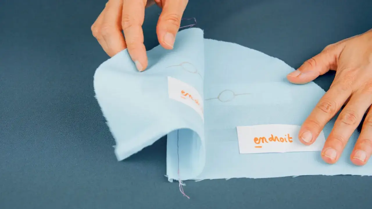 Mains tenant un tissu bleu clair, révélant un étiquette