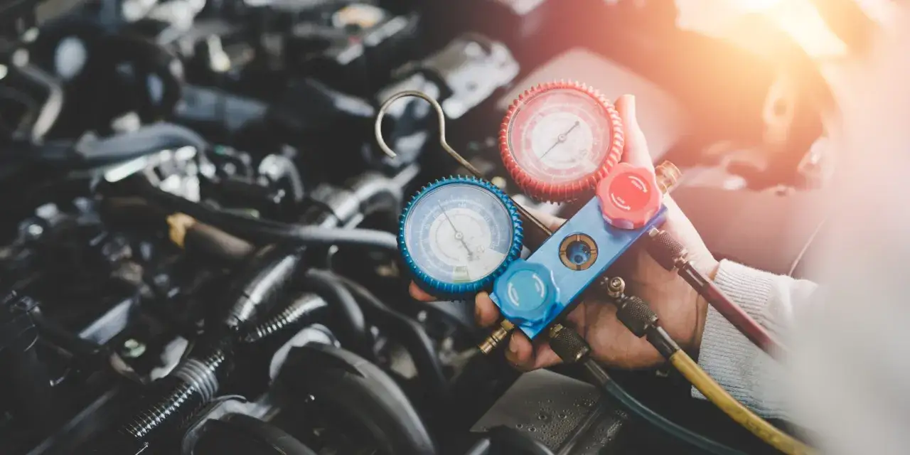 Mechanik sprawdza, ile czynnika do klimatyzacji pozostało w samochodzie, używając manometrów.