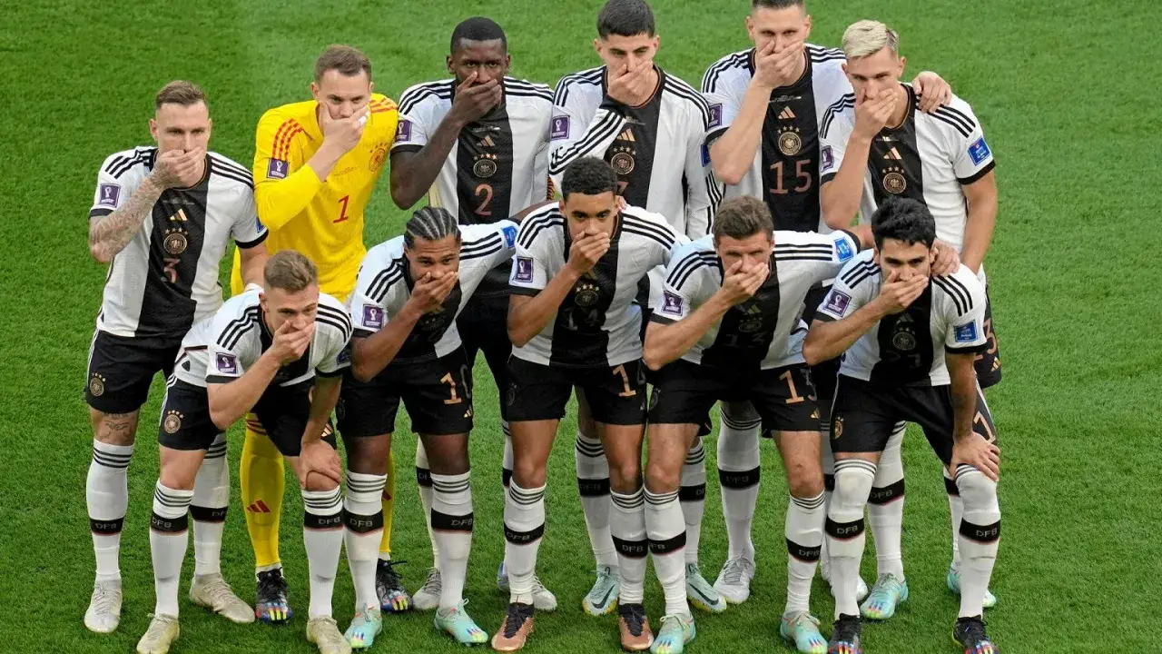 Piłkarze reprezentacji Niemiec, w tym bramkarz, zasłaniają usta. To symboliczny gest, który pokazuje, że mistrz Niemiec nie może mówić.