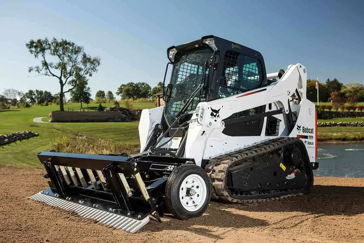 A Bobcat track loader with a landscape rake attachment, ready to tackle how to level a yard.