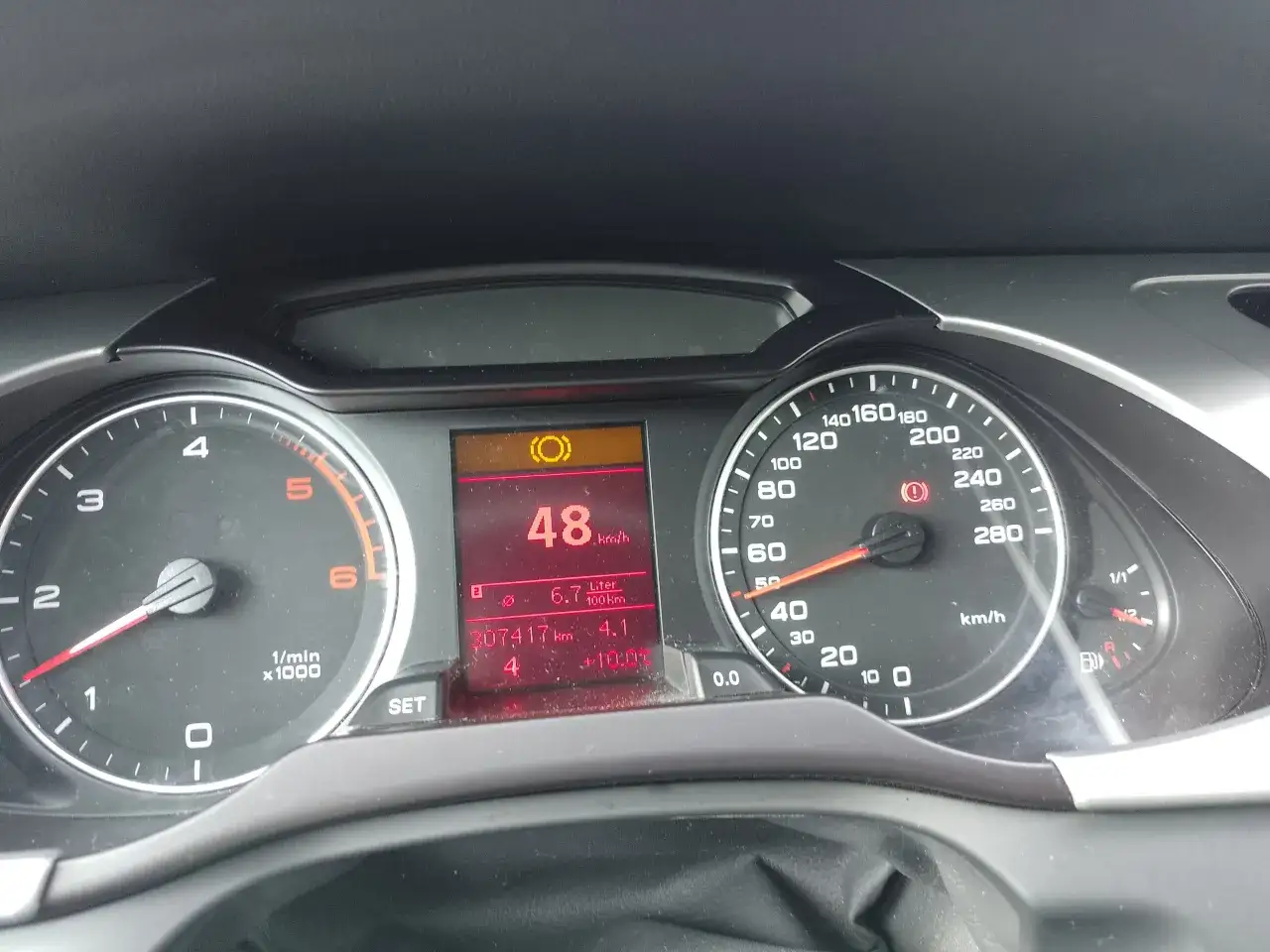 Na desce rozdzielczej świeci się żółta kontrolka hamulca. Samochód jedzie 48 km/h, spalanie 6.7 l/100km.