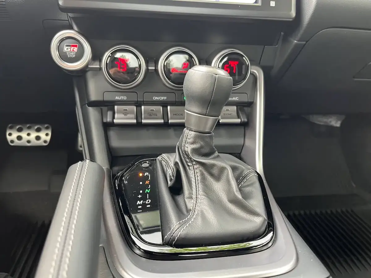 Gałka zmiany biegów z funkcją tiptronic w samochodzie sportowym. Widoczny przycisk GR Start/Stop.