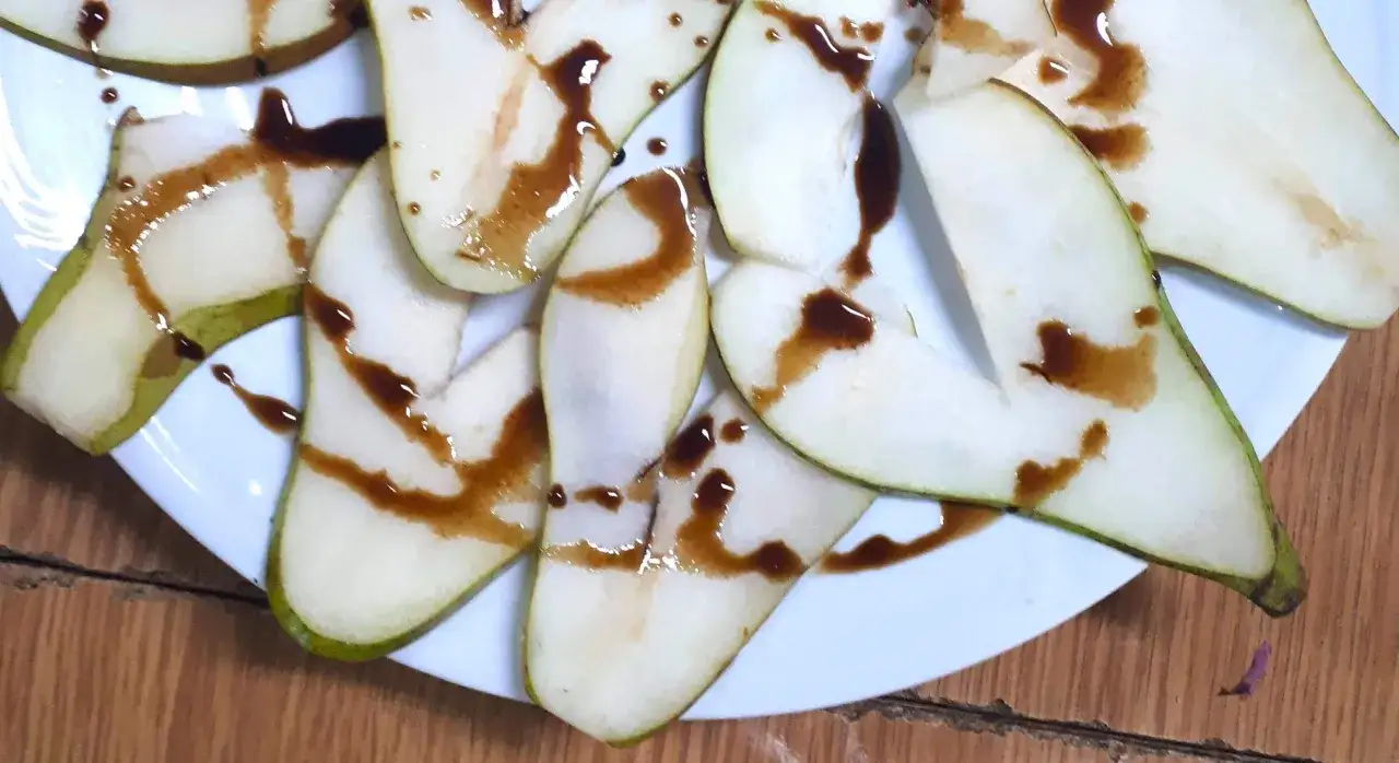 Kawałki gruszki polane gęstym, ciemnym sosem. Ocet balsamiczny do czego? Idealny do owoców, podkreśla ich słodycz.