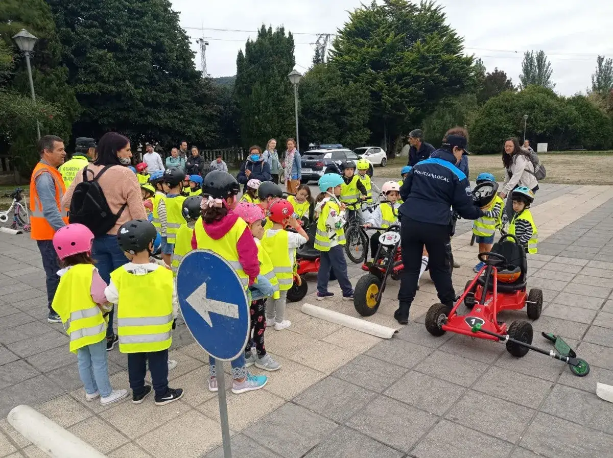 Ni&ntilde;os con chalecos reflectantes participan en juegos de educaci&oacute;n vial, aprendiendo normas de tr&aacute;fico con bicicletas y coches de pedales.