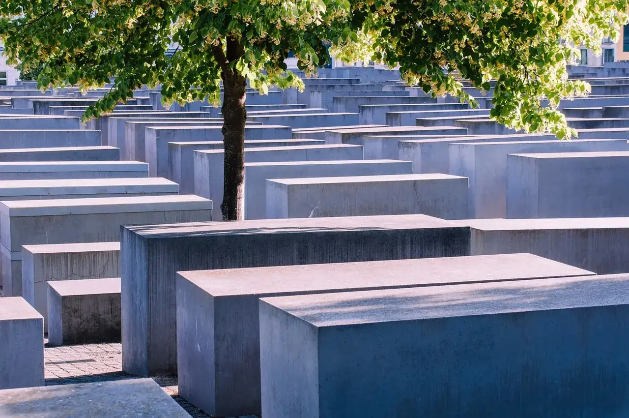 Gedenkstätte für die ermordeten Juden Europas. Betonstelen erinnern an das NS-Verbrechen. Ein Baum spendet Schatten.