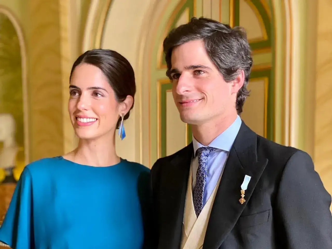 Los duques de Hu&eacute;scar, sonrientes y elegantes, posan en un sal&oacute;n dorado. Ella luce un vestido azul y &eacute;l un traje con condecoraci&oacute;n.