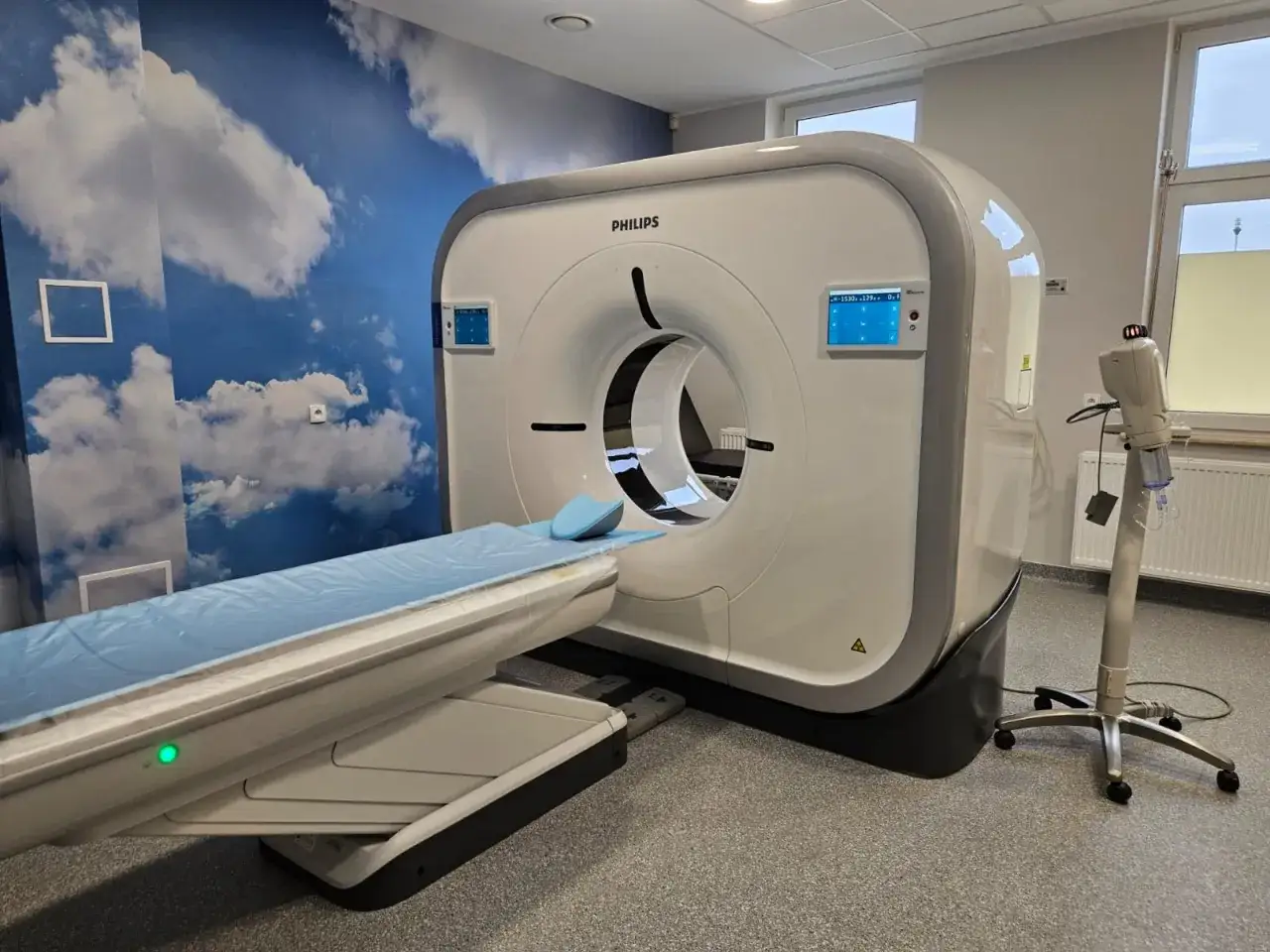 Nowoczesny aparat do tomografii głowy Philips w gabinecie z niebieską ścianą w chmury.