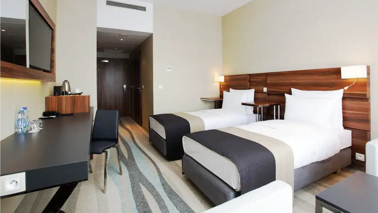 Pokój w Warsaw Plaza Hotel z dwoma łóżkami, biurkiem i telewizorem.