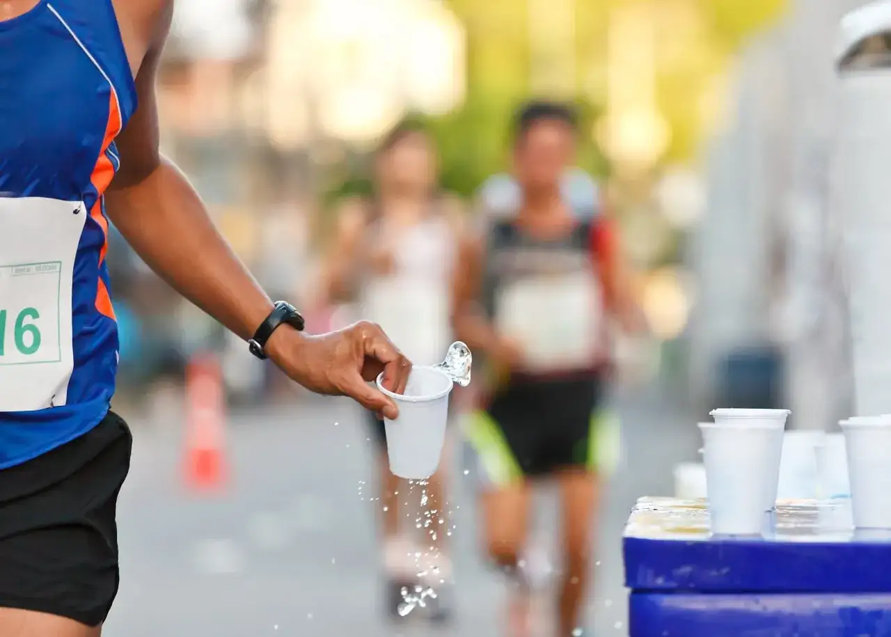 Un coureur reçoit de l'eau lors d'un marathon. L'hydratation est essentielle pour le marathon.