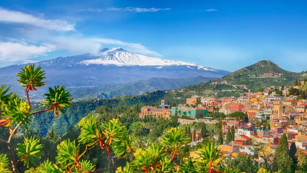 Wulkan Etna, jeden z najbardziej znanych wulkanów w Europie, góruje nad kolorowym miasteczkiem na Sycylii.