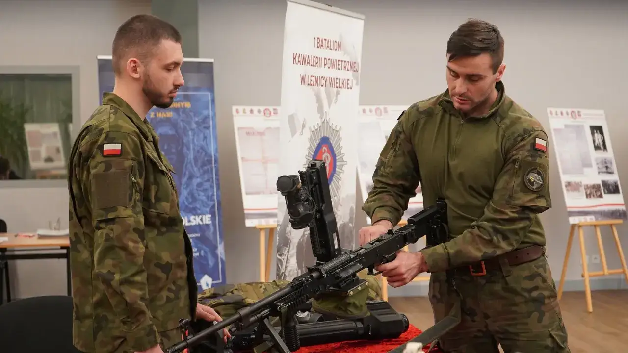 Dwóch żołnierzy w mundurach omawia karabin maszynowy. Temat: wiek poborowy w Polsce.