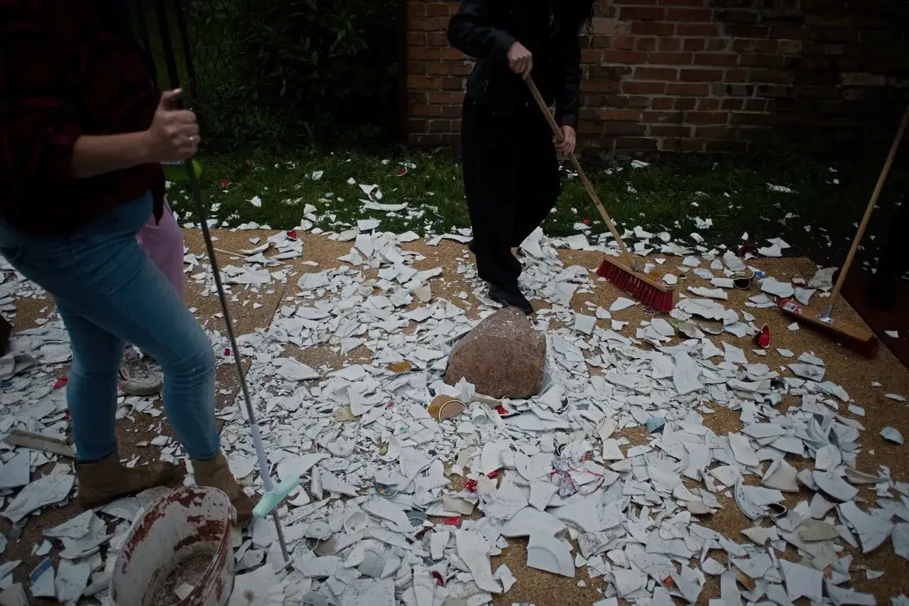 Tłuczenie szkła przed weselem, tradycja na szczęście. Ludzie sprzątają stłuczone talerze i kieliszki.