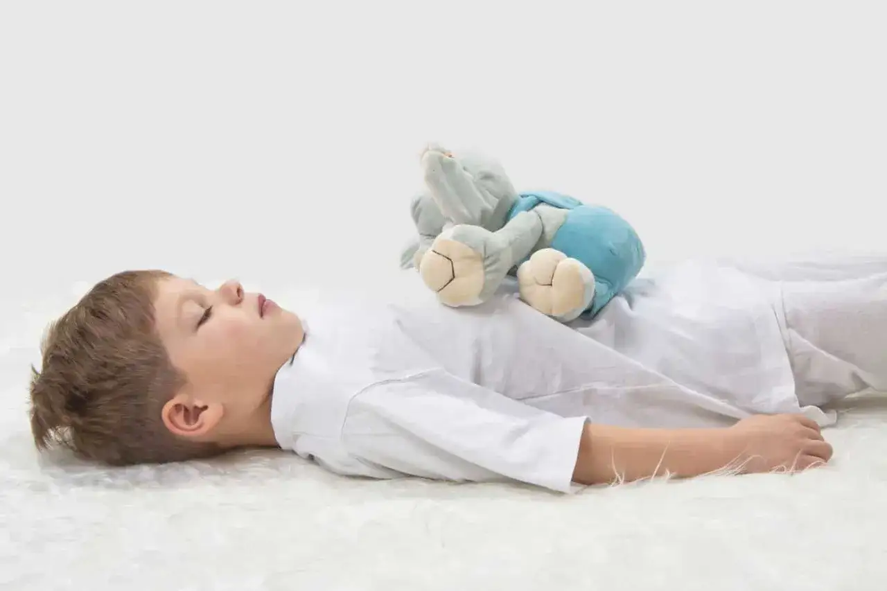 Ni&ntilde;o durmiendo con un peluche sobre su pecho, practicando ejercicios de respiraci&oacute;n para ni&ntilde;os.