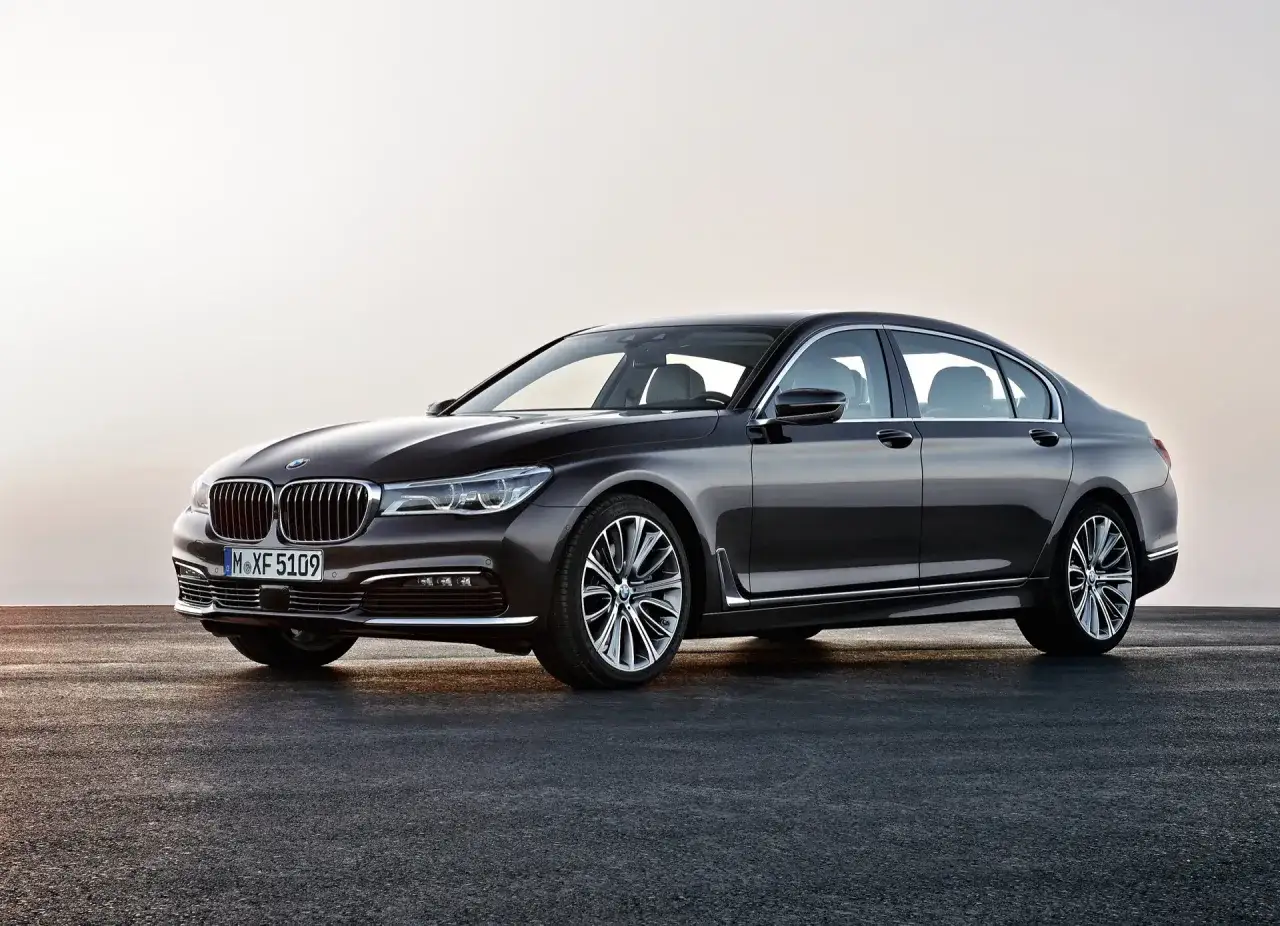 Elegancki, ciemnobrązowy **BMW 740d** prezentuje się na tle jasnego nieba.