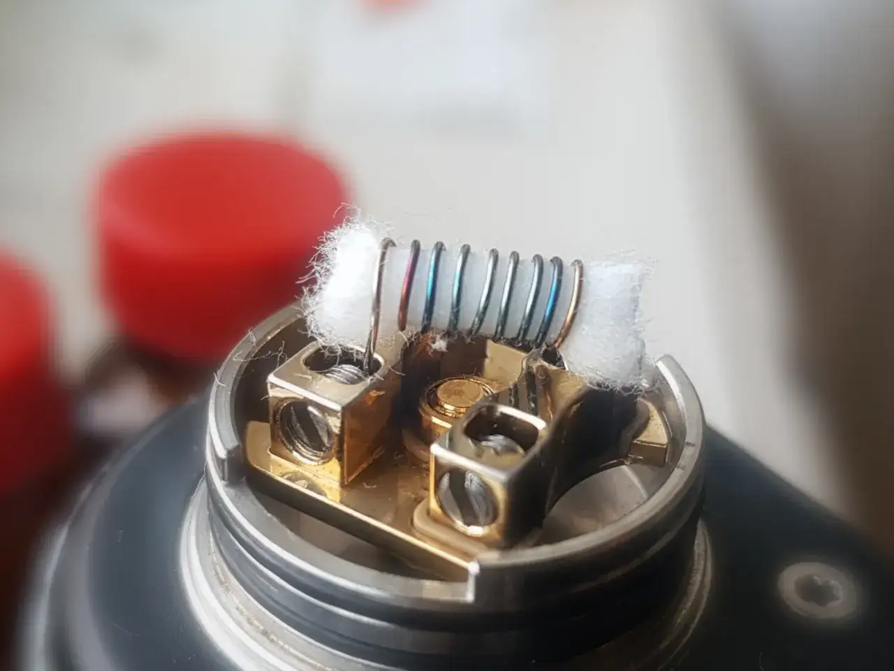Detalle de un atomizador con una **single coil** de alambre met&aacute;lico y algod&oacute;n blanco, listo para vapear.
