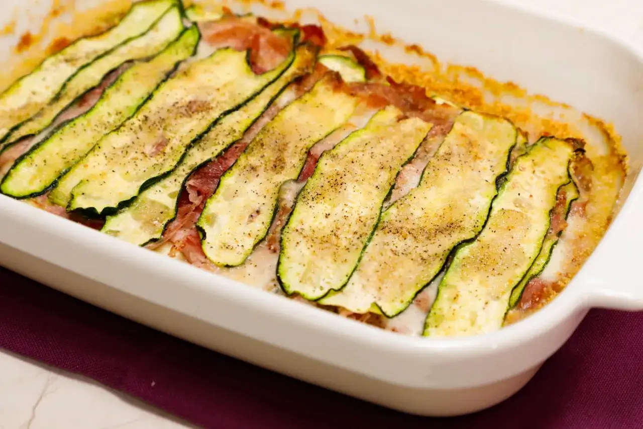 Sformato di zucchine appena sfornato, con fette sottili di zucchina dorata, prosciutto e formaggio filante.