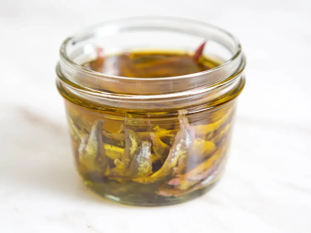 Słoik z anchois w oleju. Te małe rybki, czyli anchois, to świetny dodatek do wielu dań.