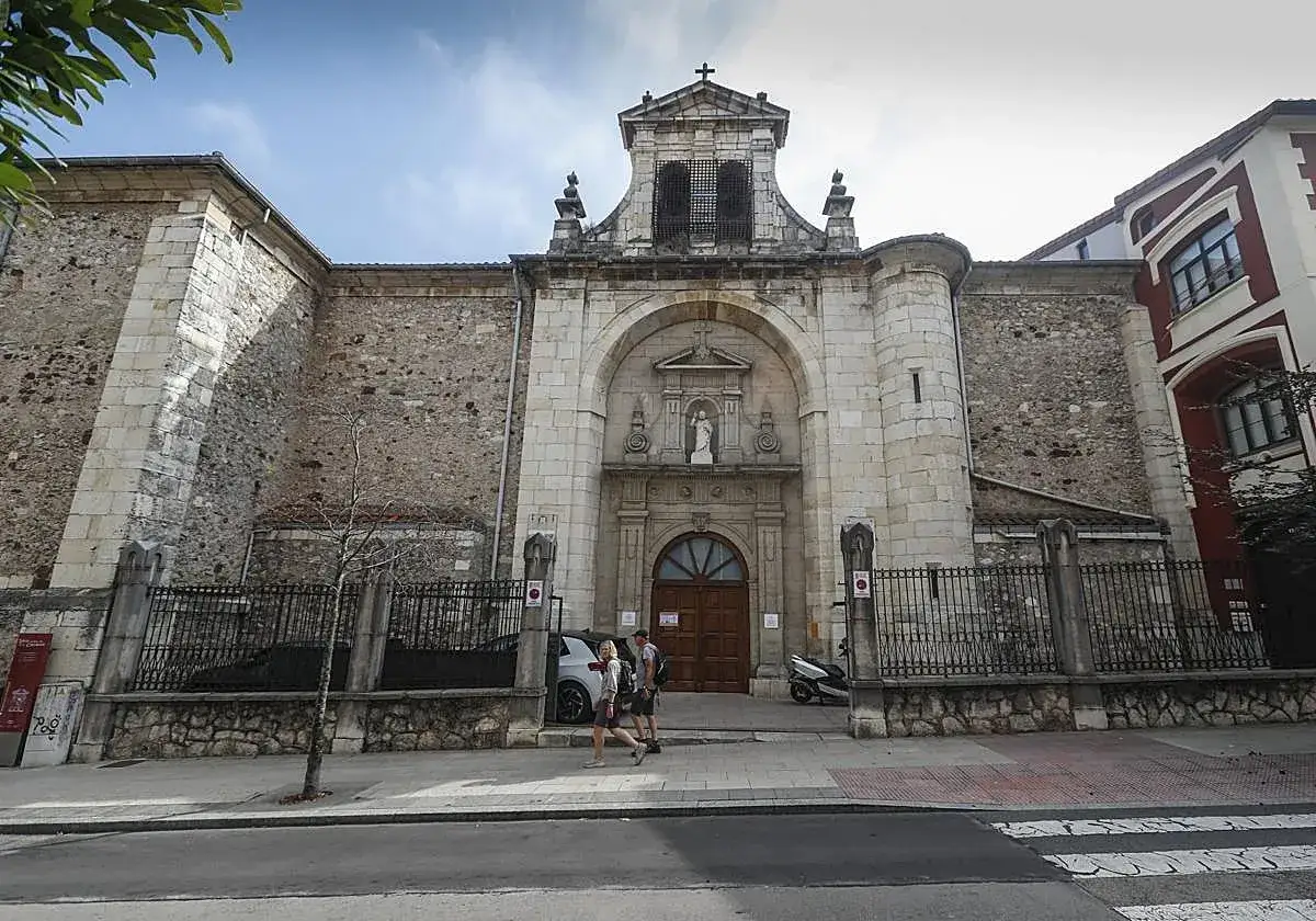 Fachada de la iglesia Consolación en Santander, con una pareja paseando por la acera.