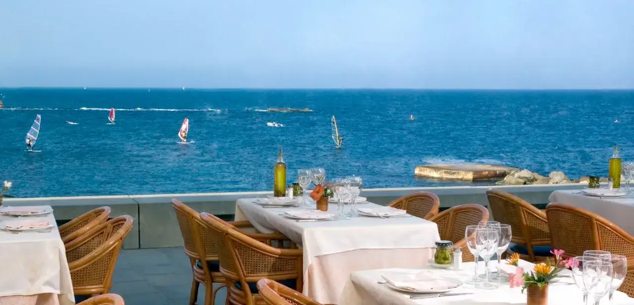 Mesas listas para disfrutar del pescaito garrucha con vistas al mar y windsurfistas.
