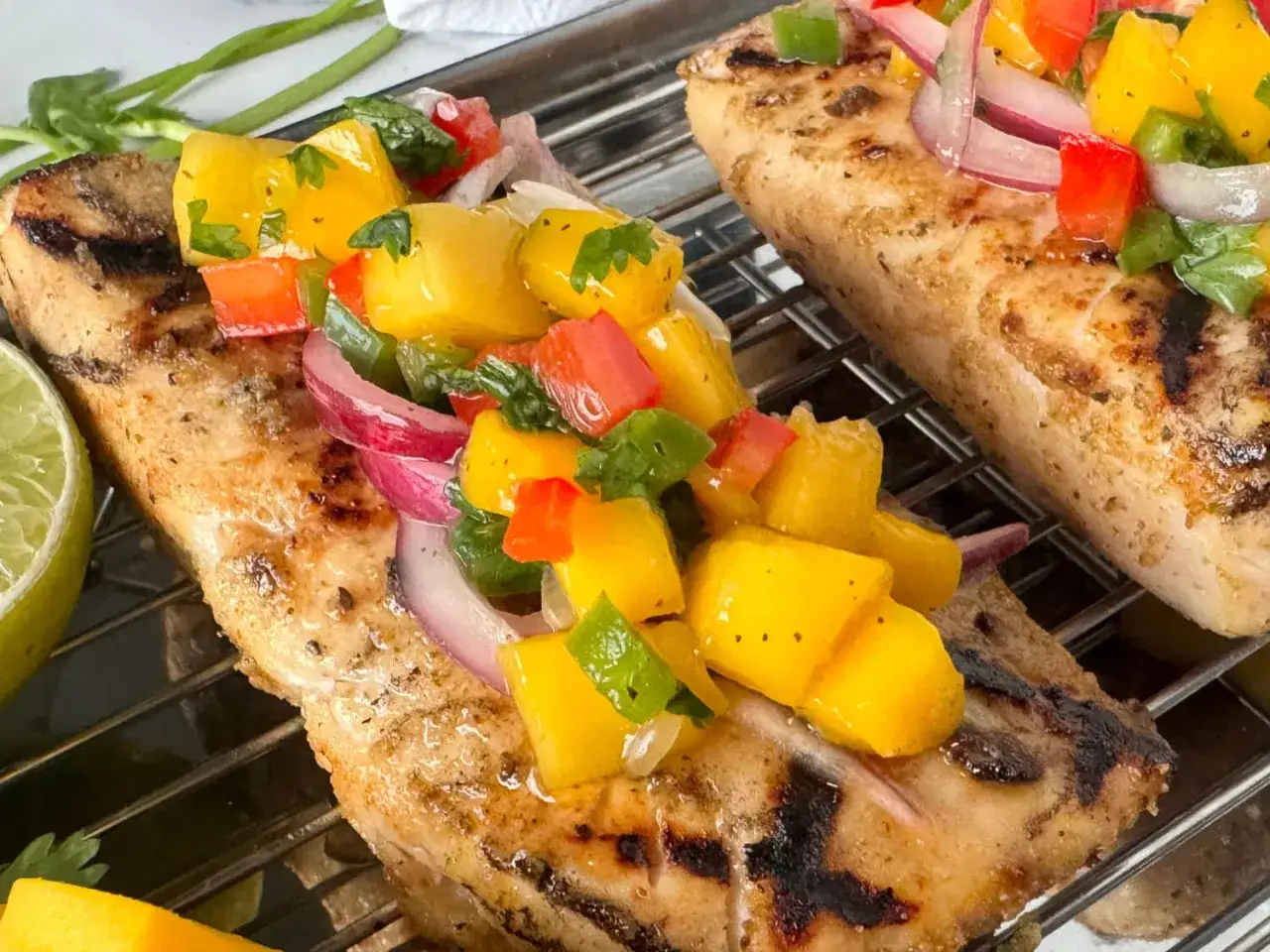 Pescado a la parrilla con una vibrante salsa de limón, mango, pimiento y cebolla morada.