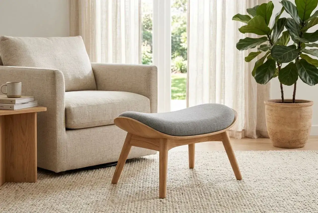 Un fauteuil confortable, un pouf design en bois et tissu gris, une plante verte et des rideaux clairs. Idéal pour un conseil décoration intérieur gratuit.