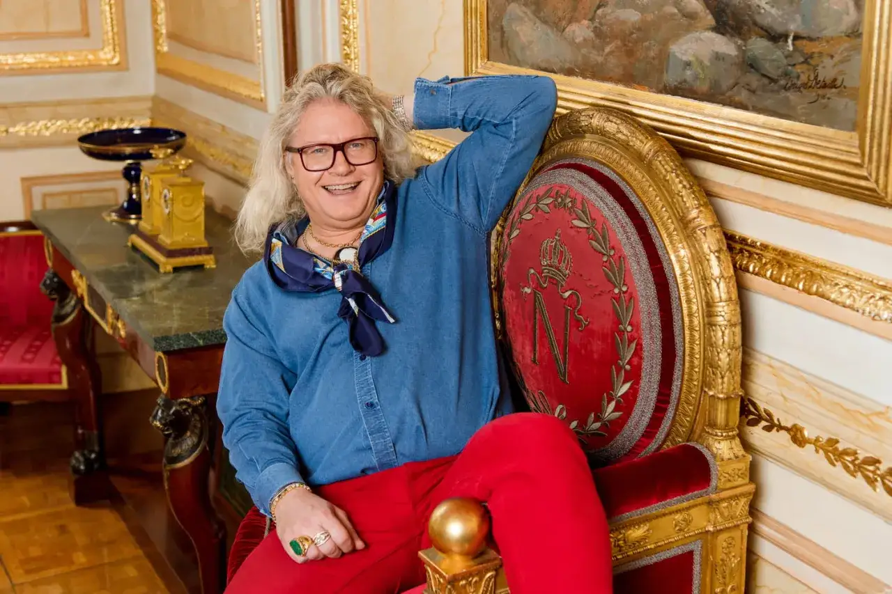 Jean Pierre Chalencon, un homme au style audacieux, pose dans un fauteuil rouge orné d'un N impérial.