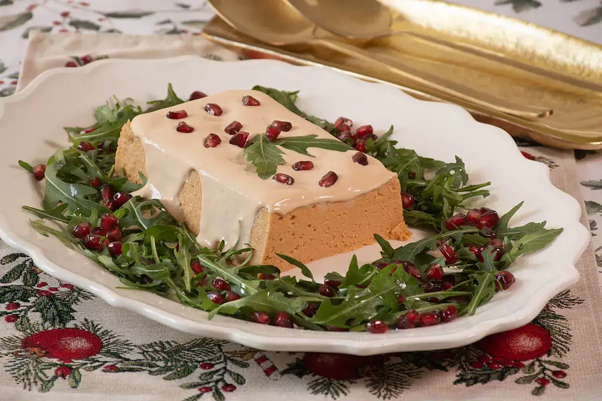 Pastel de cabracho cubierto de salsa cremosa y adornado con granada y rúcula. ¡Un plato festivo y delicioso!