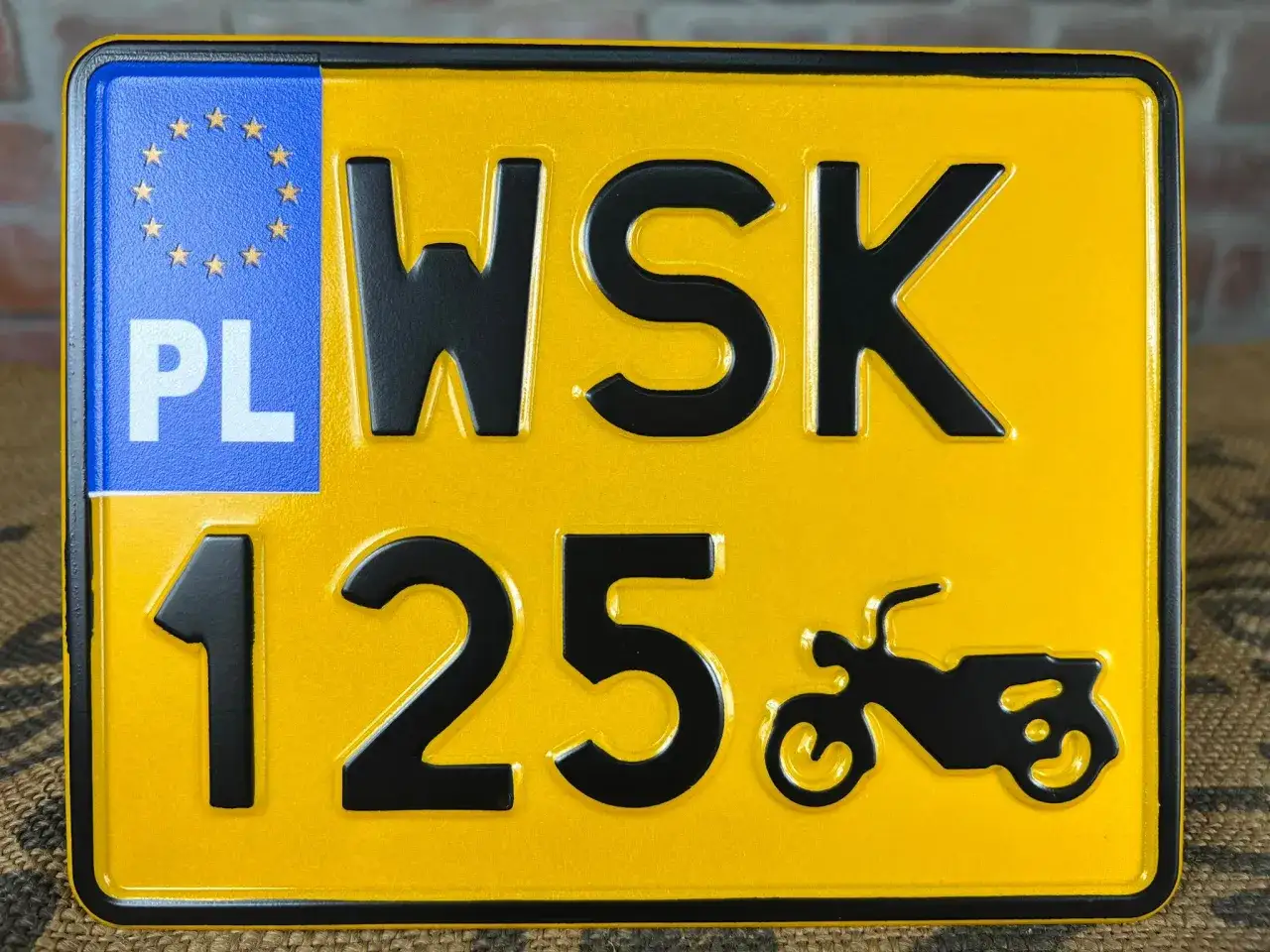 Żółta tablica rejestracyjna PL WSK 125 z symbolem motocykla.