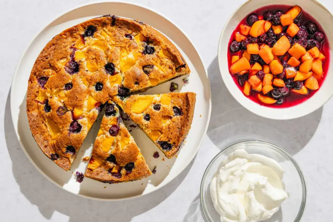Saftiger Obstkuchen aus der Springform mit Pfirsichen und Blaubeeren, dazu Fruchtsalat und Sahne. Ein tolles obstkuchen rezept springform!