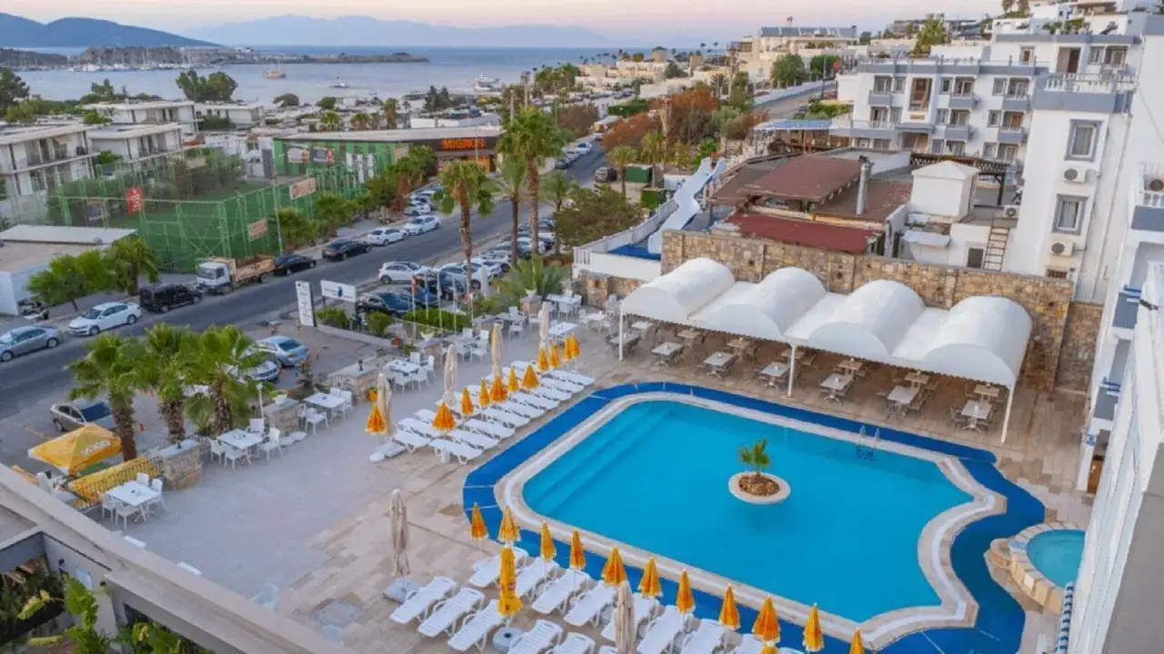 Basen i leżaki w Sunpoint Hotel Bodrum. W tle widać morze, zabudowania i drogę z samochodami.