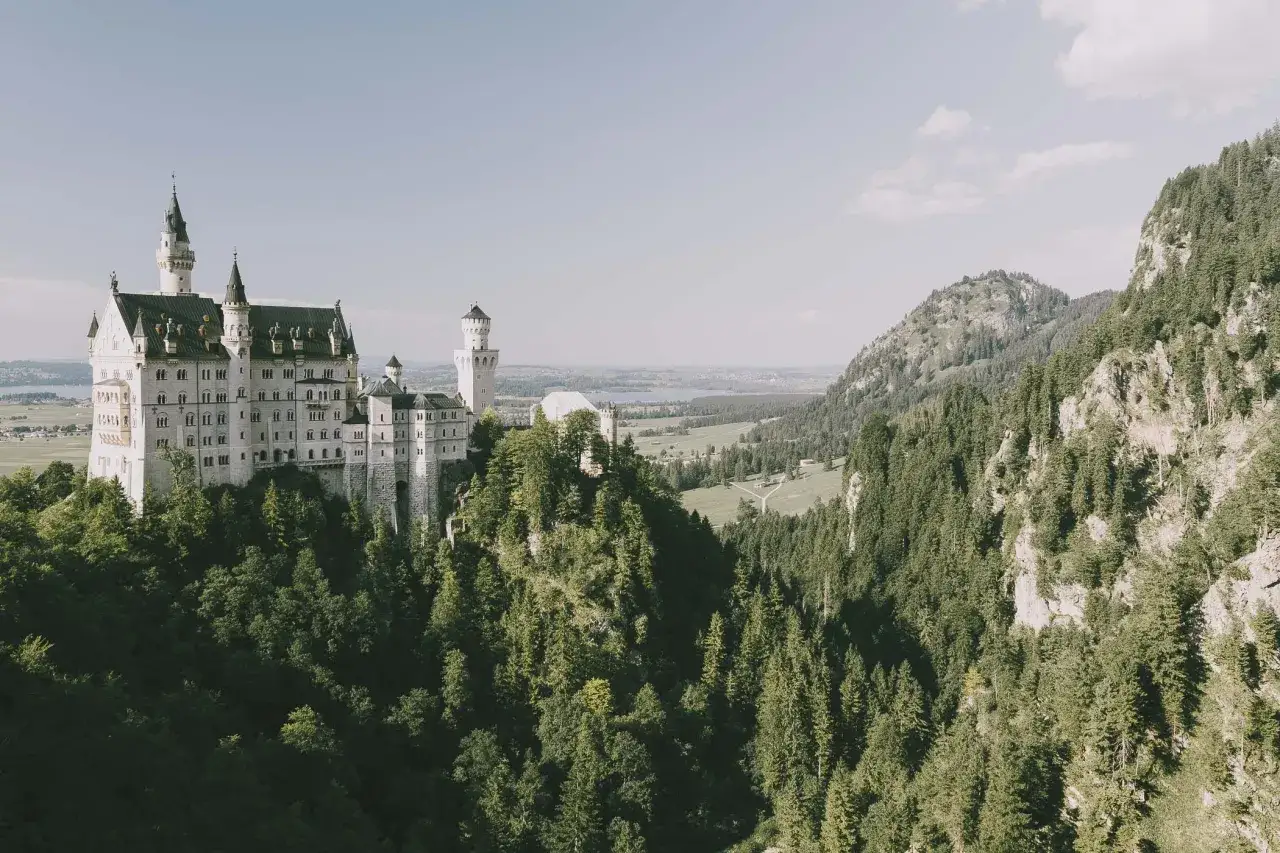 Bajkowy zamek w Niemczech, Neuschwanstein, wznosi się dumnie na tle zielonych gór i lasów.