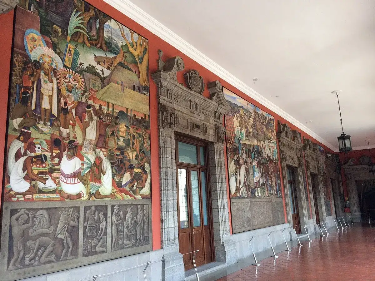 Diego Rivera murales narran la historia prehisp&aacute;nica en un pasillo con arquitectura colonial.