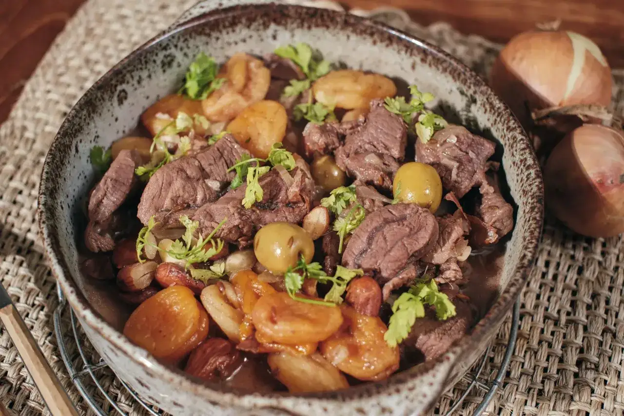 Un savoureux tajine de chevreuil mijot&eacute; avec des pommes de terre, des olives et des amandes, garni de coriandre fra&icirc;che.