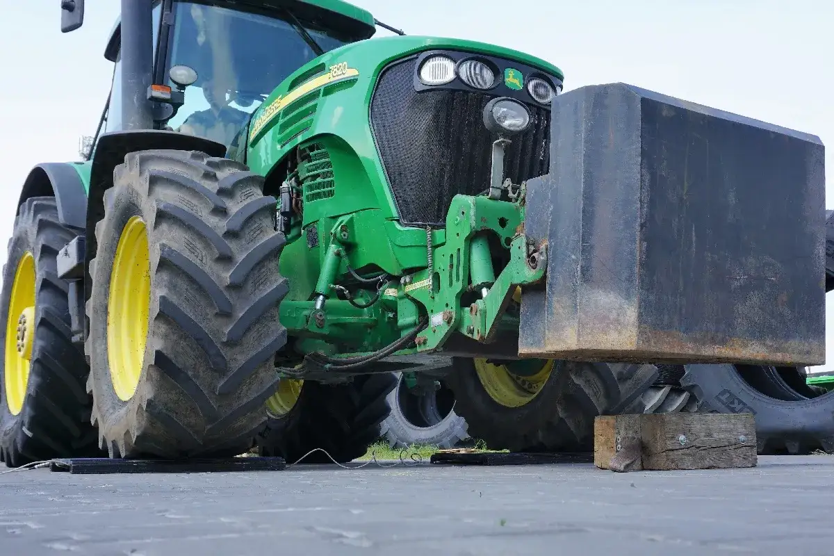 Zielony traktor John Deere z zamontowanym obciążeniem z przodu, gotowy do **tractor pulling**.