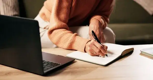 osoba pisząca list zamyślona nad kartką papieru