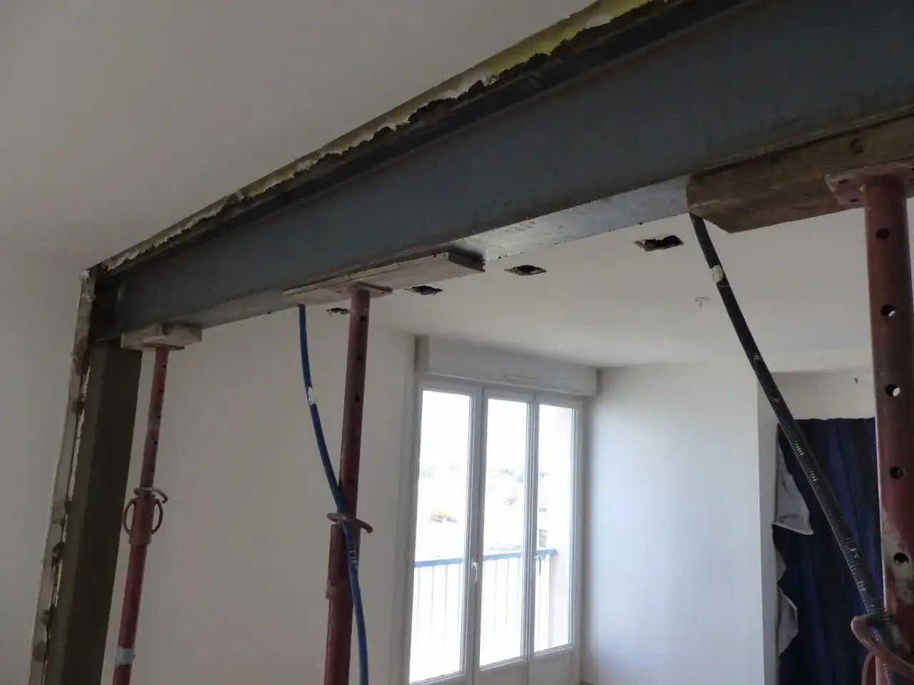 Poutre métallique soutenue par des étais, signe de travaux d'ouverture dans un appartement. Le prix de cette rénovation dépendra de l'ampleur des modifications.